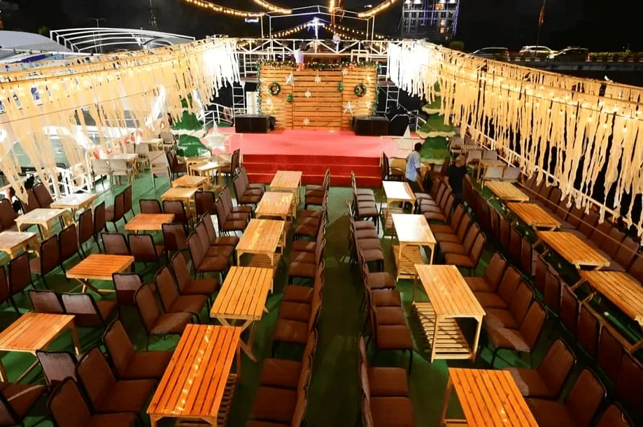 Princesa Dinner Cruise Goa seating arrangement with decorated lights and stage setup for evening entertainment.